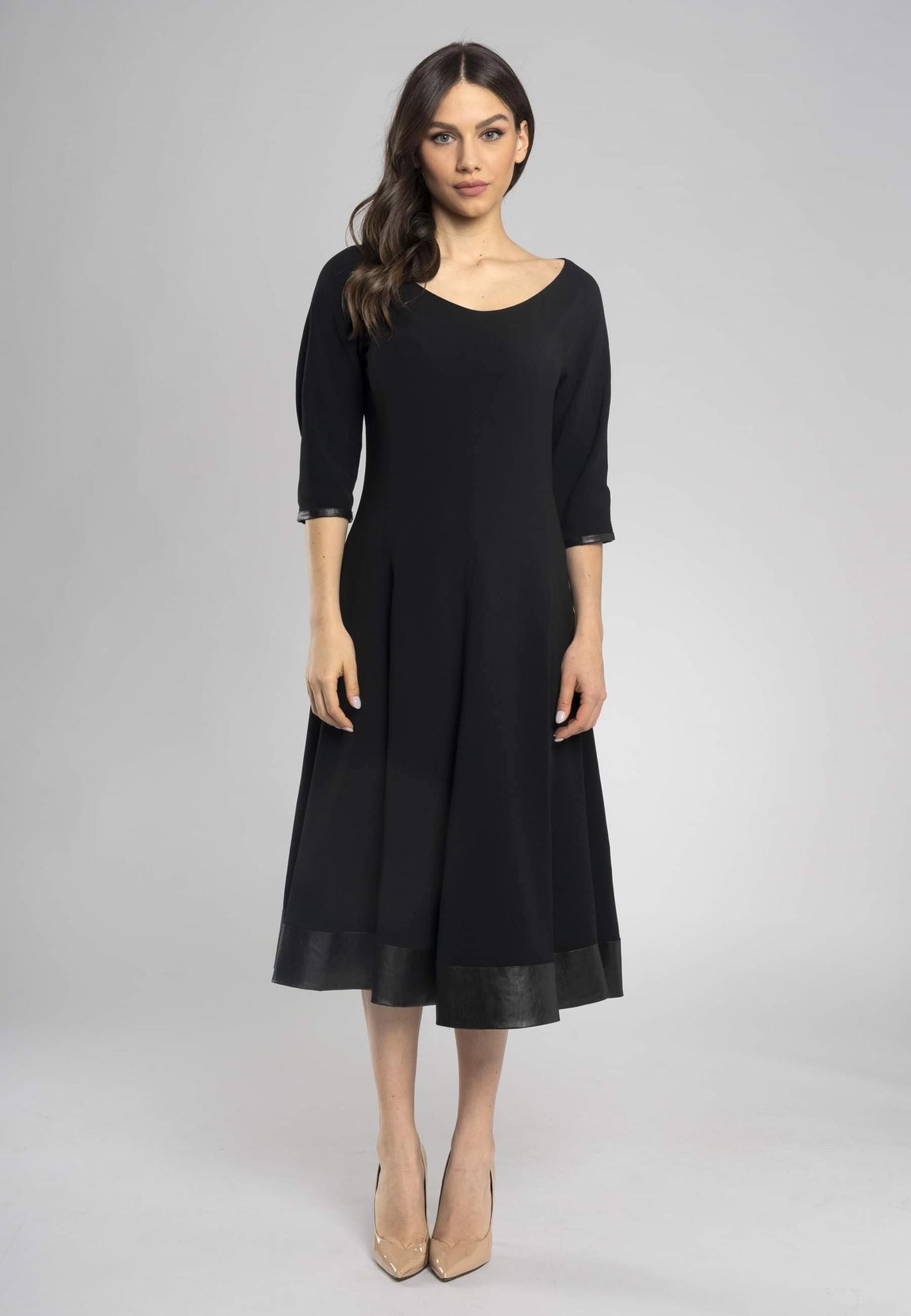 Robe noire midi à l'encolure ronde et aux manches mi-longues. Coupe raffinée et minimaliste.