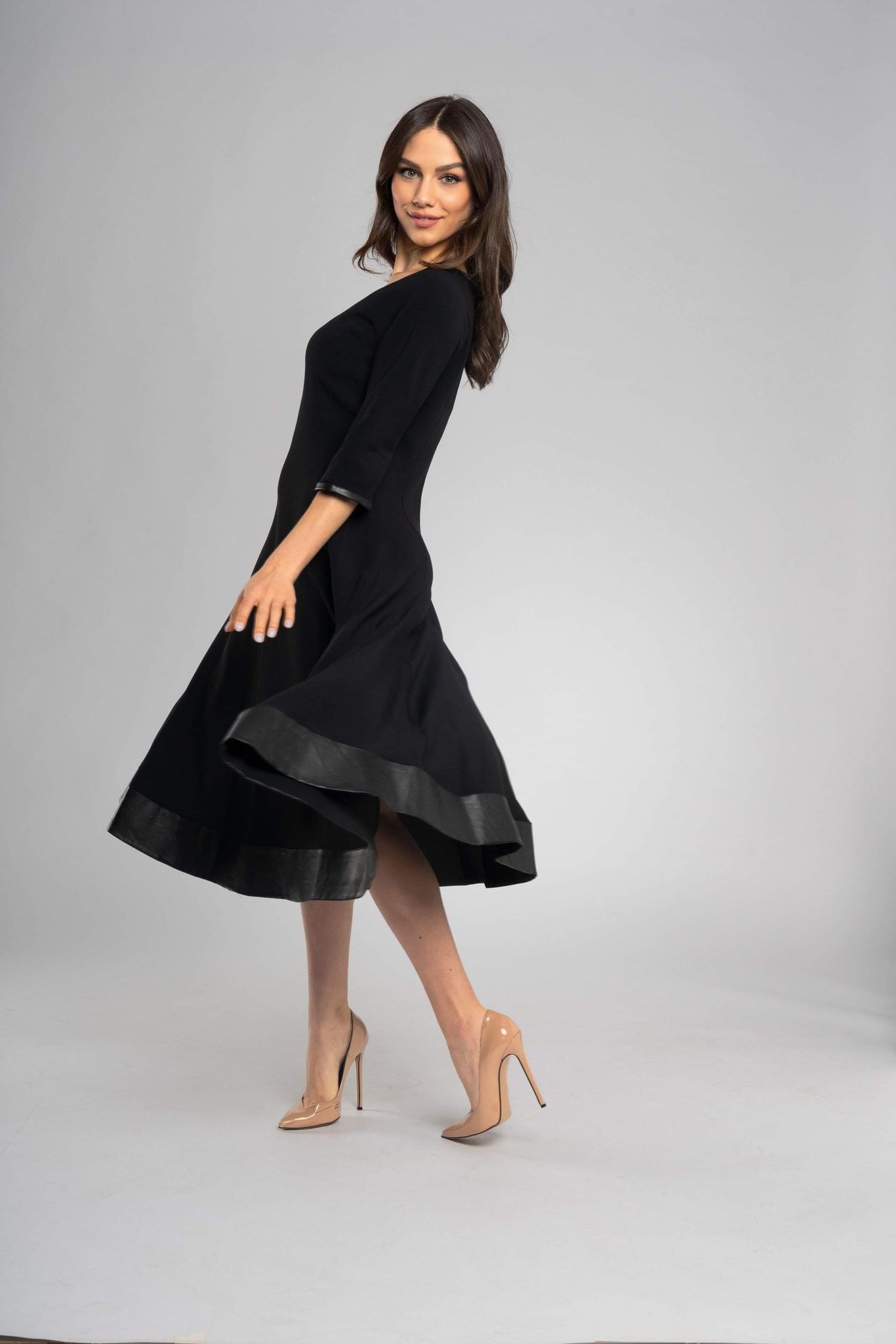 Robe noire midi à l'encolure ronde et aux manches mi-longues. Coupe raffinée et minimaliste