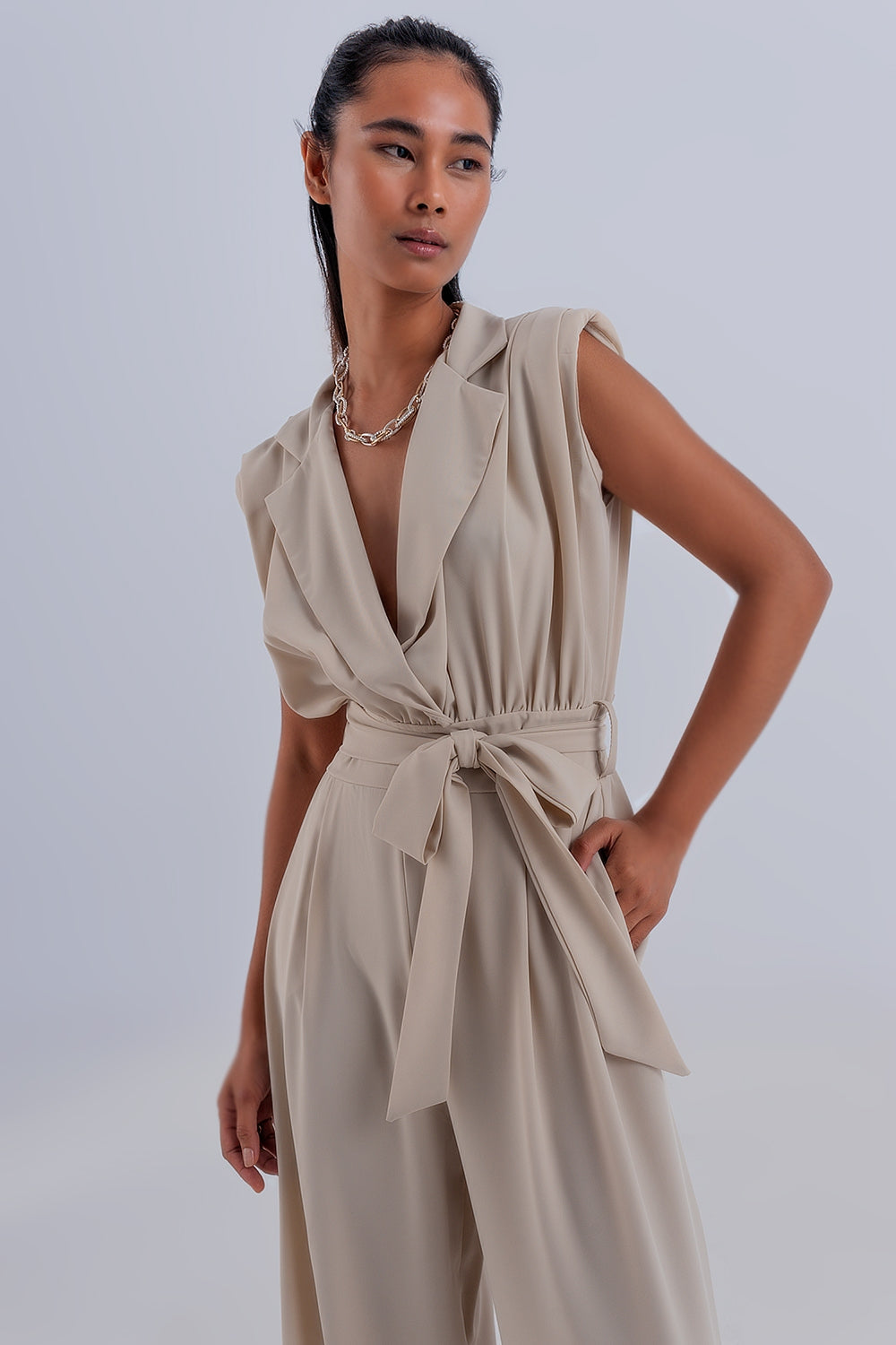 Tuta beige sartoriale, scollo a V profondo, senza maniche, look moderno e chic. Linea ampia.