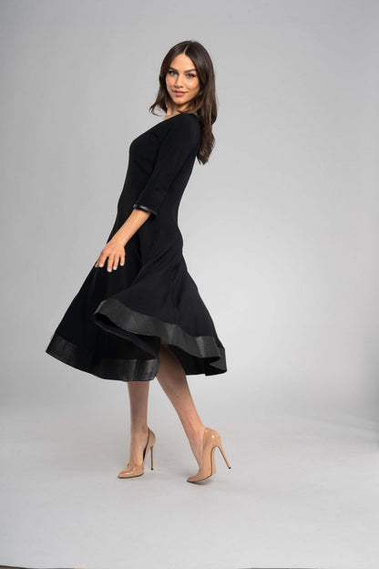 Robe noire midi à l'encolure ronde et aux manches mi-longues. Coupe raffinée et minimaliste
